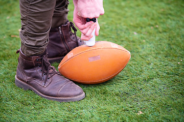 Image showing man pumping air into american football ball