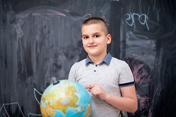 Image showing boy using globe of earth in front of chalkboard