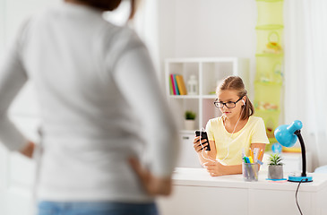 Image showing girl listening to music and mother entering room