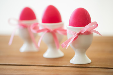 Image showing pink colored easter eggs in holders on table