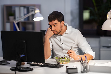 Image showing businessman with computer eating at night office