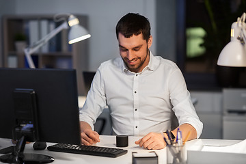 Image showing businessman using smart speaker at night office