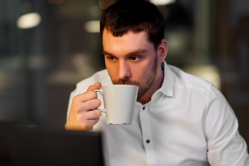 Image showing businessman drinking coffee at night office