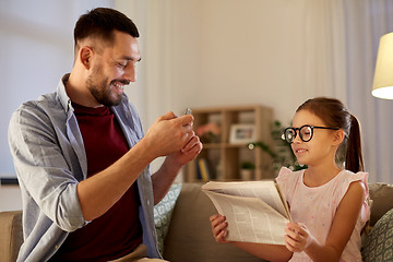 Image showing father photographing daughter by cellphone at home