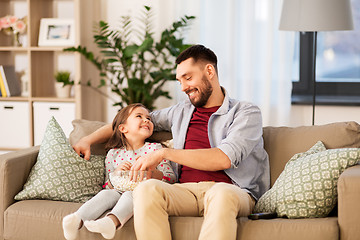 Image showing happy father and daughter eating popcorn at home