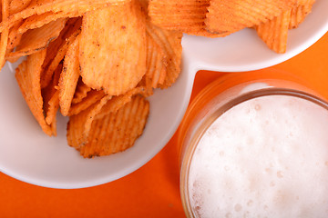 Image showing Glass of light beer and potato chips on a abstract background. top view