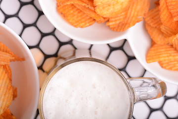 Image showing Glass of light beer and potato chips on a abstract background. top view