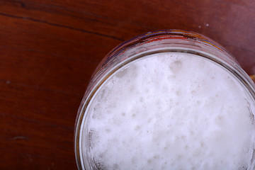 Image showing Glass of beer foam over wooden table