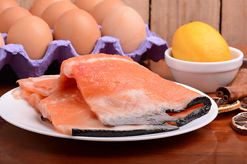 Image showing fresh salmon fillet close up on white plate. eggs, cinnamon and lemon