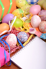 Image showing Handcrafted easter eggs close up, white notepad, ribbons and decoration