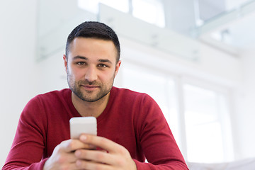 Image showing young man using a mobile phone  at home