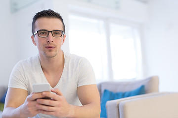 Image showing young man using a mobile phone  at home