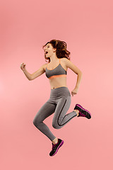 Image showing Freedom in moving. Pretty young woman jumping against orange background