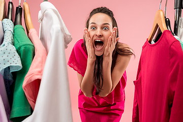 Image showing The young pretty girl looking at dresses and try on it while choosing at shop