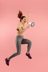 Image showing Beautiful young woman jumping with megaphone isolated over red background