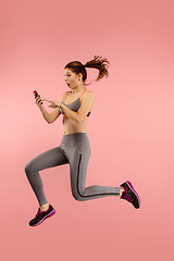 Image showing Full length of pretty young woman with mobile phone while jumping