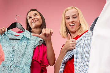 Image showing The two young pretty girls looking at dresses and try on it while choosing at shop