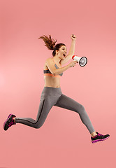 Image showing Beautiful young woman jumping with megaphone isolated over red background