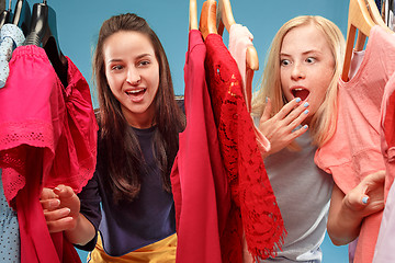 Image showing The two young pretty girls looking at dresses and try on it while choosing at shop