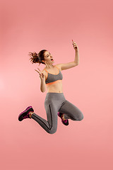 Image showing Full length of pretty young woman with mobile phone while jumping