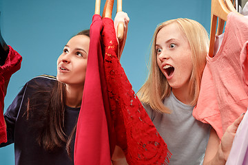 Image showing The two young pretty girls looking at dresses and try on it while choosing at shop