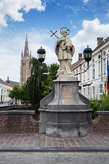 Image showing Bruges, Belgium - August 16, 2013: Statue of Johannes Nepomucenus and the church tower against the blue sky in Bruges