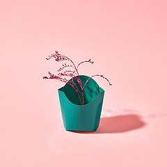 Image showing A colored branch in a green cardboard box on a pink background with copy space. Creative layout for postcards.