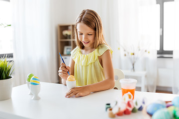 Image showing happy girl coloring easter eggs at home