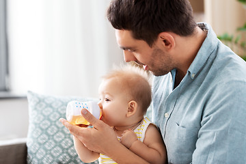 Image showing father giving baby daughter to drink from bottle