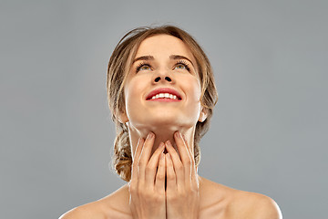 Image showing smiling young woman touching her neck