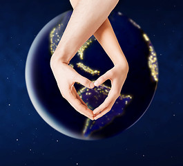 Image showing hands showing heart gesture over earth in space