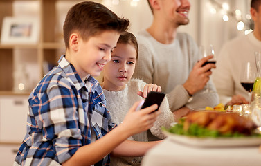 Image showing boy with sister using smartphone at family dinner