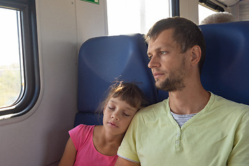 Image showing Girl sleeping leaning on dad\'s shoulder in an electric train car