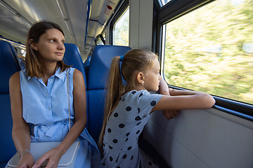 Image showing Mom and daughter in an electric train car, look out the window with enthusiasm