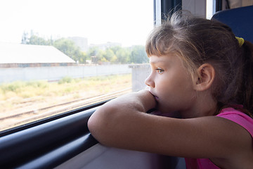 Image showing A girl of eight years looks out the window in an electric train