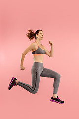 Image showing Freedom in moving. Pretty young woman jumping against orange background