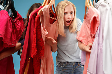 Image showing The two young pretty girls looking at dresses and try on it while choosing at shop