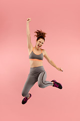 Image showing Freedom in moving. Pretty young woman jumping against orange background