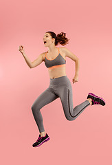 Image showing Freedom in moving. Pretty young woman jumping against orange background