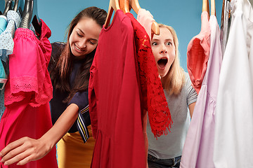 Image showing The two young pretty girls looking at dresses and try on it while choosing at shop