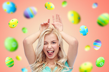 Image showing happy smiling young woman making easter bunny ears