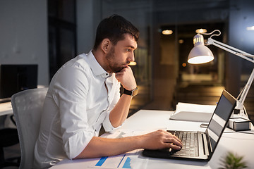 Image showing businessman with laptop working at night office