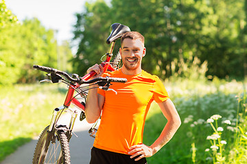Image showing happy young man with bicycle outdoors in summer