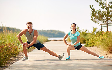 Image showing smiling couple stretching legs on beach