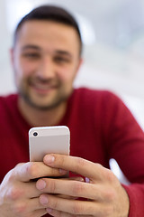 Image showing young man using a mobile phone  at home