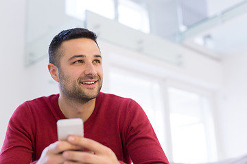 Image showing young man using a mobile phone  at home