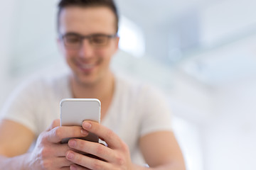 Image showing young man using a mobile phone  at home