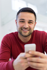 Image showing young man using a mobile phone  at home