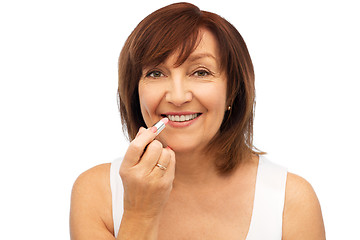 Image showing smiling senior woman applying lipstick to her lips