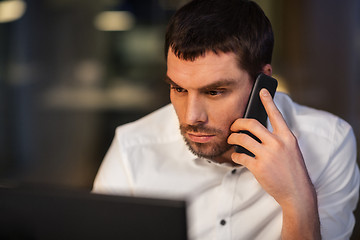 Image showing businessman calling on smartphone at night office